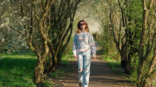 Woman Moving Through Spring Blooming Park Concept of Lonely Walk