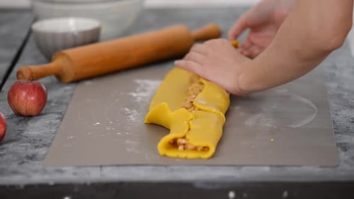 A Woman is Preparing Cookies with Apple Filling on a Table in a Bakery