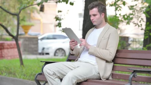 Young Adult Using Tablet on Park Bench