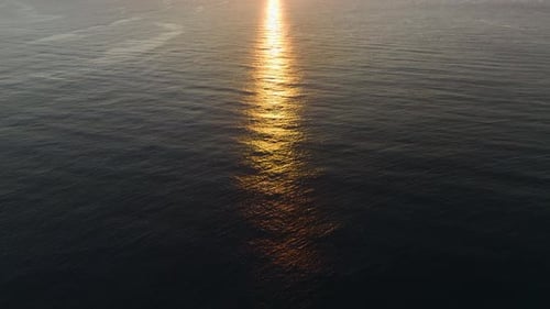 Luftvideo Wunderschöne Meeresoberfläche bei Sonnenuntergang mit goldenen Strahlen, die sich auf ruhigem Wasser spiegeln