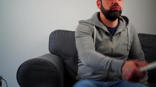 Man Sitting on Couch with Remote Control