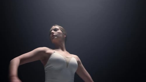 Ansicht von unten auf eine hübsche Tänzerin, die sich im dunklen Raum dreht. Nahaufnahme Flexibel