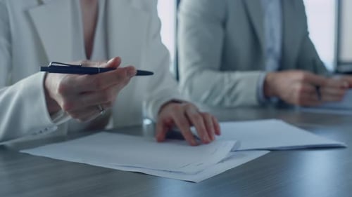 Business professionals sign documents at office desk