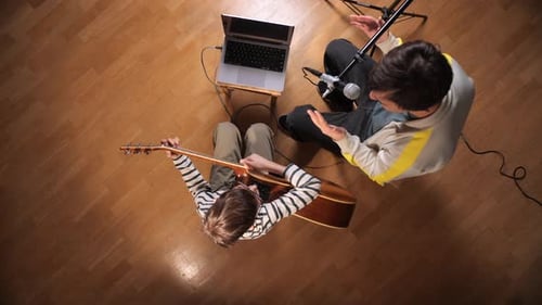 Child learns guitar with tutor in home studio