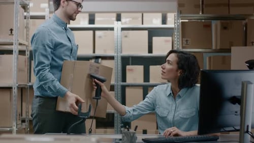 Female Inventory Manager Scans Cardboard Box with Barcode Scanner, Worker Puts Package on the Desig