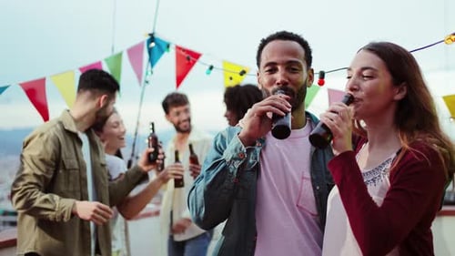 Friends Celebrating at Rooftop Party, Drinking Beer