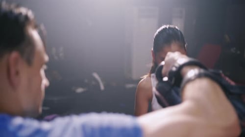 Woman Boxing With Trainer at Smoky Gym