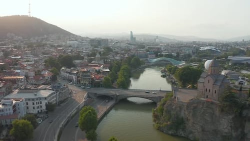 Aerial view of Metekhi church in downtown Tbilisi, Georgia at sunset, sunrise with mountains in the