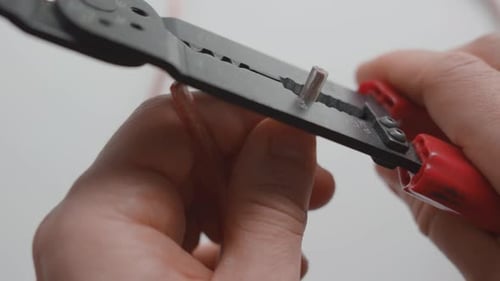 Man stripping two electrical wires with a wire stripper tool. Close up