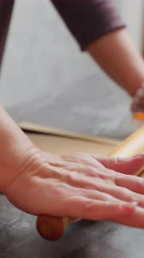 Woman rolling out dough with wooden rolling pin