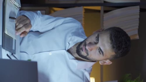 Man Working Late at Desk with Book