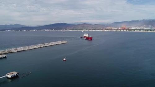 Aerial view of tug boats assisting an empty cargo ship to the Manzanillo Port, in cloudy Mexico