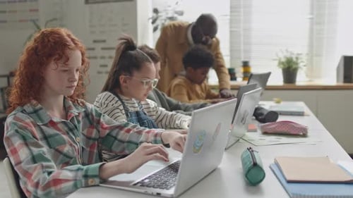 Colegiala pelirroja codificando en una computadora portátil en el aula