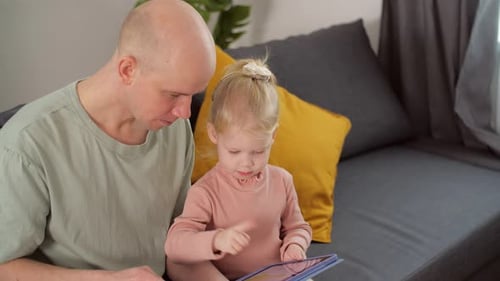 A Child with Cochlear Implants Plays with a Tablet Computer with His Father
