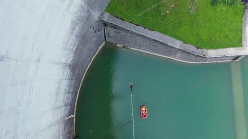 Aerial drone view of young girl hang swinging the bungee jumping cord off a 50m high dam platform .R