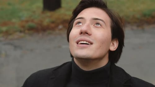 Smiling Young Man Looking Upward in a Park