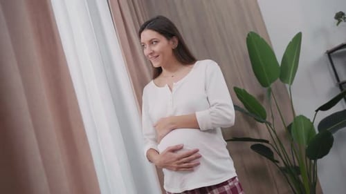 Caucasian Healthy Looking Pretty Young Woman Pregnant Expecting Child Hugging Baby Belly and Looking