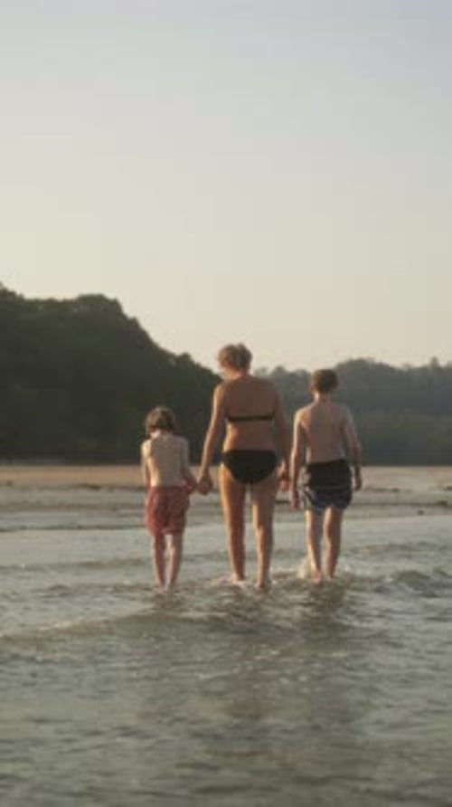 Family Walking Together in Shallow Water at Beach