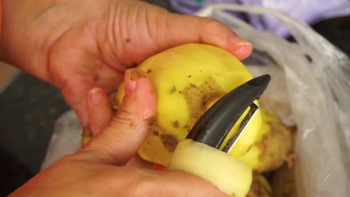 peeling potatoes close up with a potato peeler