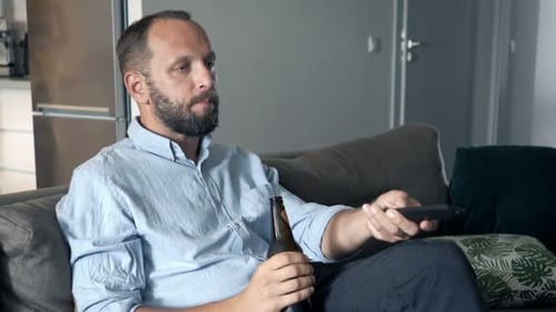 Man drinking beer and watching television at home