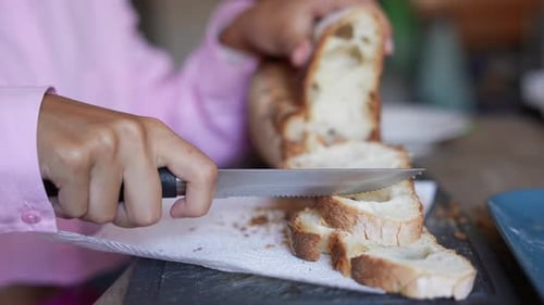 Person Slices Crusty Bread with Serrated Knife