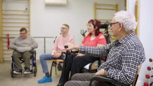 Adults Sitting in Wheelchairs in Therapy Room