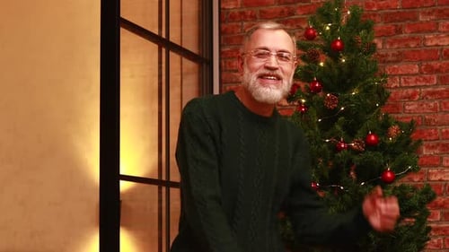 an Elderly Man in a Green Knitted Sweater Dancing Near the Christmas Tree