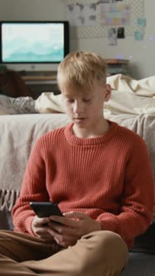 Teenager Sits On Floor Using a Mobile Phone