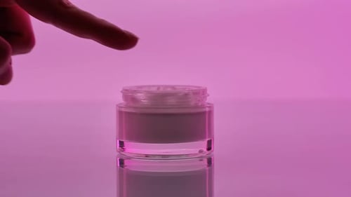 Hand Dipping Finger in Skincare Cream Jar CloseUp Image