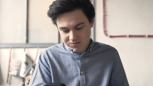 Young Teenager with Smartphone Eating Hamburger Sitting in Cafe Alone