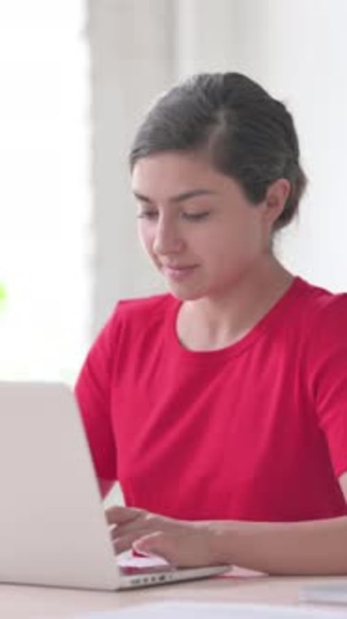 Indian Woman Looking at Camera while using Laptop in Office, Vertical Video