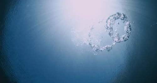 Blasen unter Wasser mit Sonnenstrahlen im durchsichtigen blauen Meer. Luftblasen in den Pool bringen