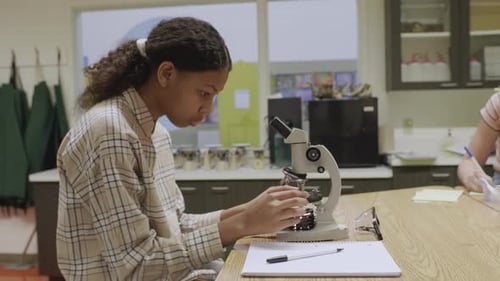 Konzentrierter Gymnasiast führt wissenschaftliches Experiment am Mikroskop im Labor durch