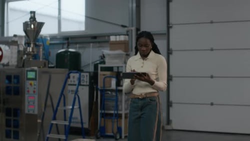 Portrait of Woman Walking with Tablet Amidst Machinery in coffee Roastery Plant