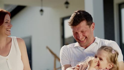 Happy Family Laughing Together Outside Suburban Home