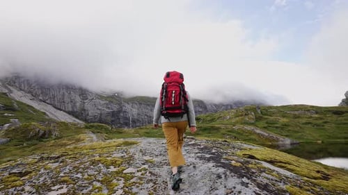 Girl with a Big Red Backpack Hikes Through the Highlands of Norway