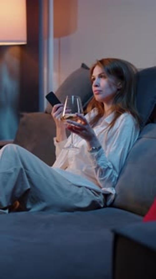 Woman Sitting on Sofa with Wine Glass Under Changing Light
