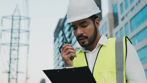 Porträt eines bärtigen Bauunternehmers, der auf der Baustelle Informationen im Radio austauscht