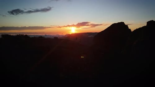 wide view of two people hiking a mountain ridge during golden sunset, pastel blue sky, pearl clouds