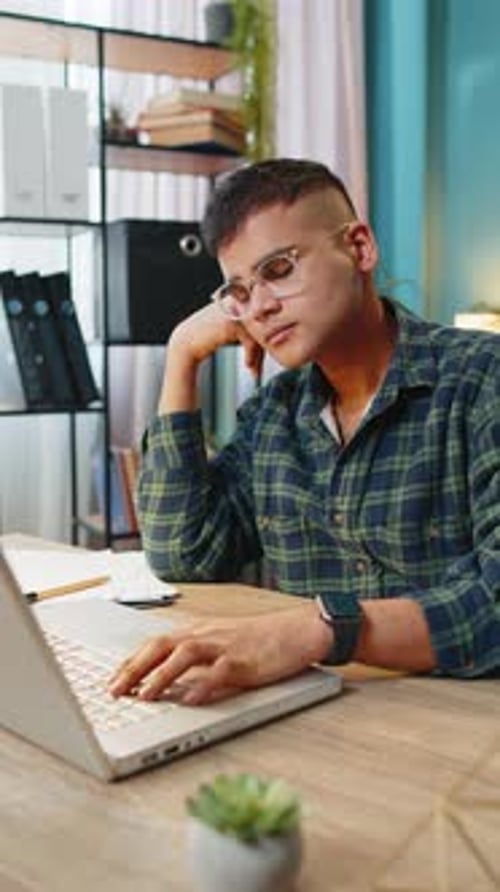 Bored Sleepy Business Man Worker Working on Laptop Computer Yawns Leaning on Hand at Office Desk