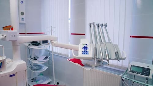 Modern dental cabinet. Empty stomatology office with clean medical tools near the red dental chair.
