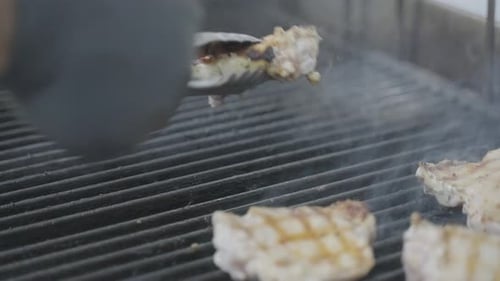 Grilled chicken legs on barbecue, turning with tongs