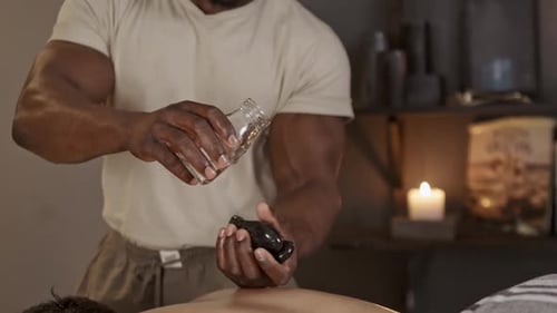 Masseuse with oil on stones for massage at a spa for back therapy, wellness and self care
