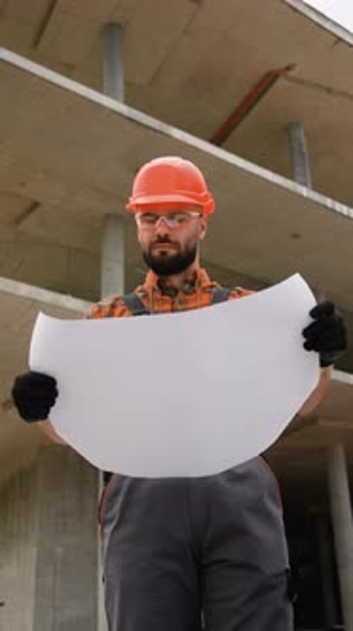 Construction Worker Holding Blank Blueprint on Building Site