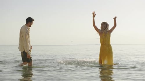Couple Enjoying a Playful Moment in Shallow Water During Sunset at a Beach Splashing Each Other with