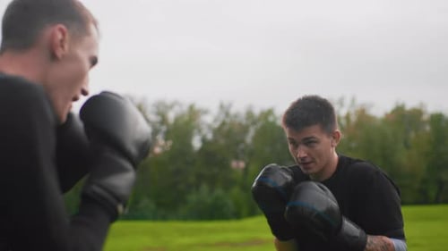 Men sparring outdoors with boxing gloves on