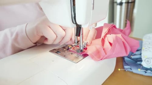 Woman Sewing Pink Fabric with Machine at Home