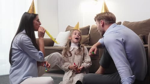 Family Celebrating Birthday Together with Party Blowers