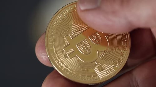 A close up shot of a unrecognized person's hand holding golden bitcoin. Secure cryptocurrency storag