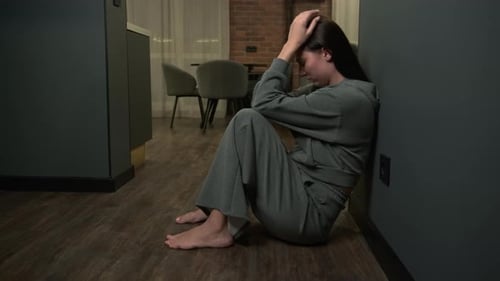 A Sad Woman During Depression Sits on the Floor at Home and Cries